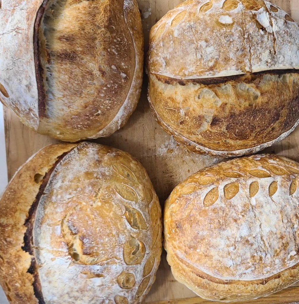 Four loaves of Artisan sourdough bread on a wooden board